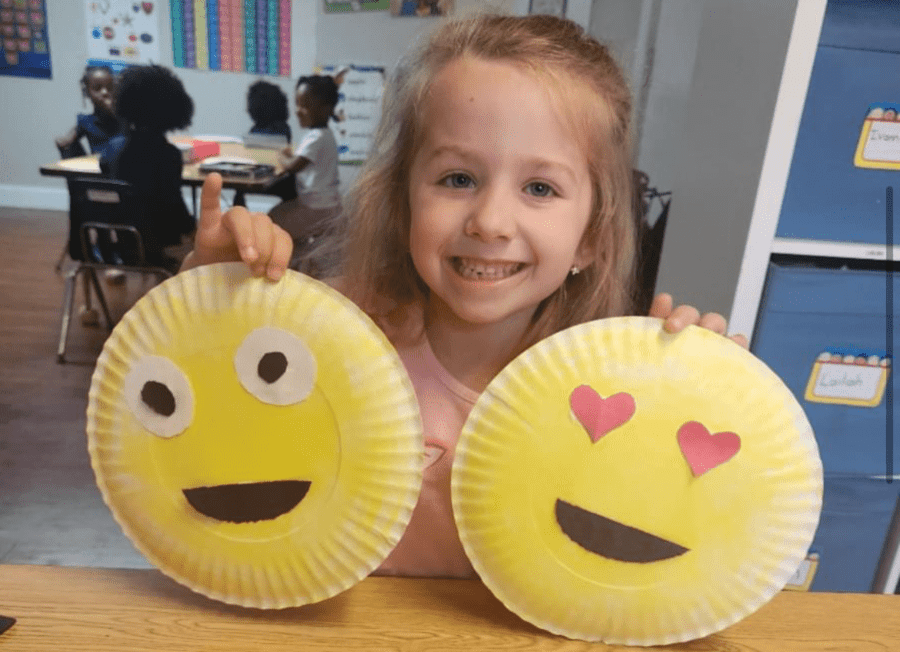 Pre-K student holding up Happy Face project